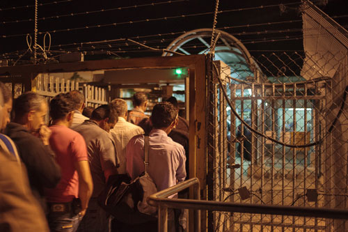 Para pekerja Palestina pertama harus melewati serangkaian pintu putar logam yang dikendalikan jarak jauh. Pintu ini merupakan fitur yang ada banyak pos pemeriksaan di Tepi Barat. Di Eyal, petugas keamanan mengontrol alur para pekerja ini lewat sebuah bilik tertutup. Pekerjaannya yang lain adalah membuka gerbang dan mengizinkan warga Palestina masuk ke ‘israel’ secara satu per satu. foto: Daniel Tepper/Electronic Intifada