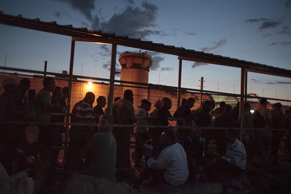 Seorang pria Palestina dan ayahnya berada di dekat perapian sebelum mengantri masuk ke ‘israel’. foto: Daniel Tepper/Electronic Intifada