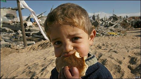 Seorang bocah Gaza menggigit potongan roti di depan rumah yang hancur dibom zionis Yahudi. foto: AFP