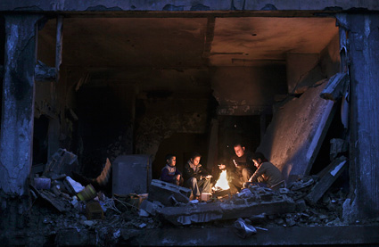 Seorang ayah dan anak-anaknya menghangatkan badan di sebuah reruntuhan bangunan di Beit Lahiya, Gaza Utara. foto: MSNBC