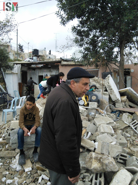Keluarga Amro berdiri di puing-puing rumah mereka yang hancur. Foto: ISM