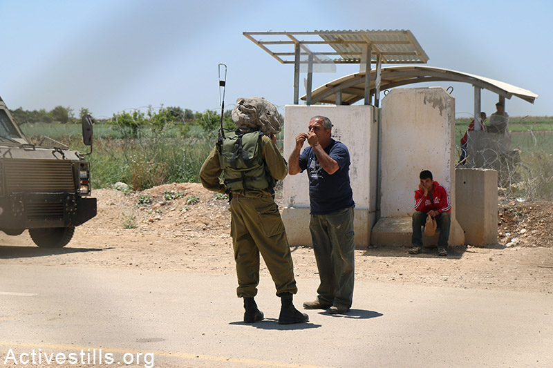 Petani Palestina berdebat dengan seorang tentara Zionis di sebelah barat pagar pemisah di desa Falamya. Foto: Ahmad al-Bazz/Activestills.org