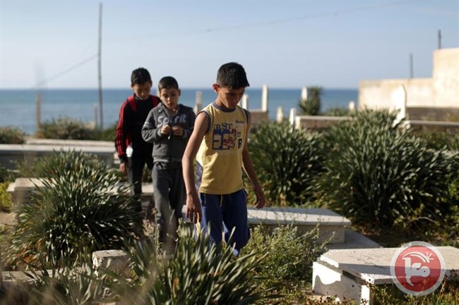 Anak-anak Palestina dari keluarga Bakr, yang selamat dari serangan militer Zionis di pantai Gaza mengunjungi makam kerabat tercinta mereka. Foto: AFP/Mahmud Hams