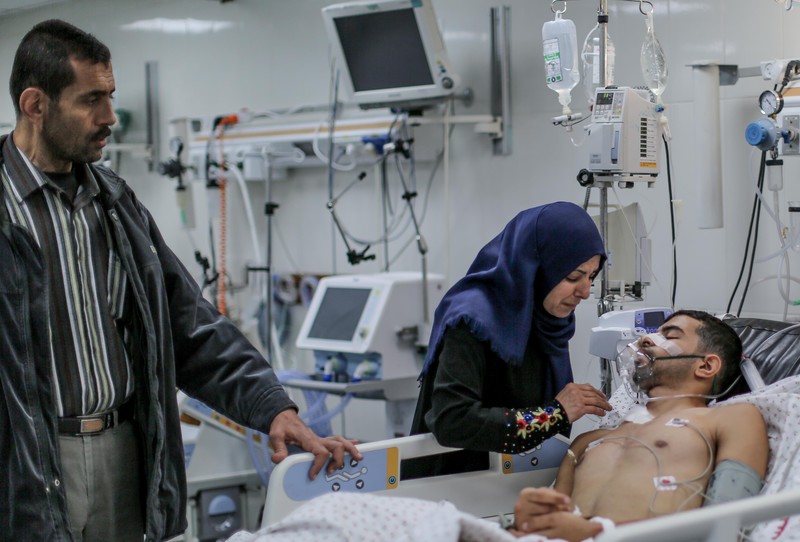 Muhammad al-Bhaisy dikunjungi orangtuanya di rumah sakit al-Shifa, Gaza, sebelum dipindahkan ke ‘Israel’ untuk menjalani perawatan. Foto: Ezz Zanoun