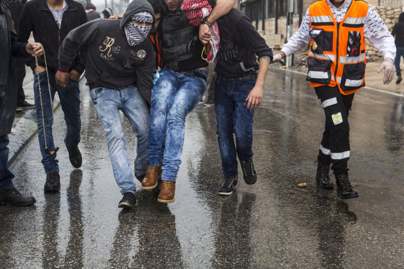 Warga Palestina menggotong demonstran yang terluka. Sejumlah pemuda terluka, termasuk tiga orang terkena tembakan saat aksi demo. Foto: Anne Paq