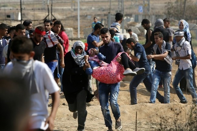 Demonstran Palestina yang terluka akibat gas airmata dievakuasi rekan-rekan mereka saat terjadi bentrokan dengan pasukan keamanan Zionis di dekat pelintasan perbatasan Nahal Oz, di timur Kota Gaza pada 10 Oktober lalu. Foto: AFP/Mahmud Hams