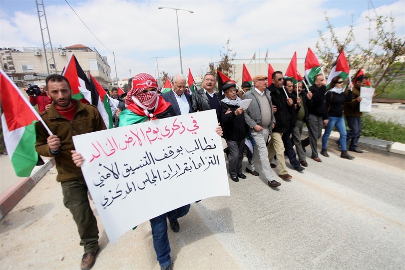 Warga Palestina memegang spanduk yang mengecam “koordinasi keamanan” antara pasukan penjajah ‘Israel’ dan Otoritas Palestina saat demo Hari Tanah di dekat penjara Ofer di Tepi Barat terjajah, 30 Maret lalu. Foto: Hamza Shalash/APA images