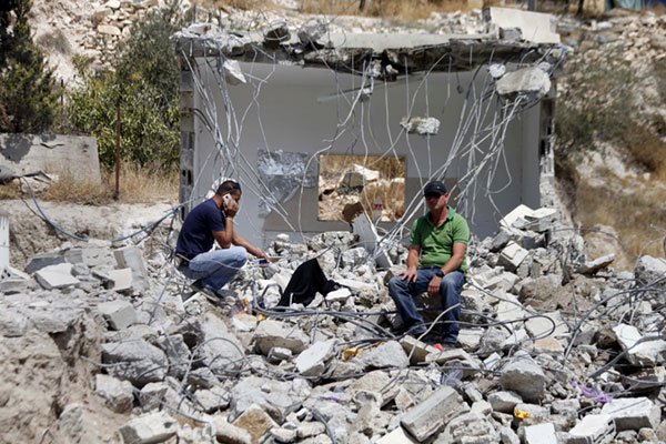 Saker Jaabis duduk di atas reruntuhan rumah di Jabel Mukaber, Baitul Maqdis, yang dihancurkan oleh otoritas ‘Israel’. Foto: MEMO