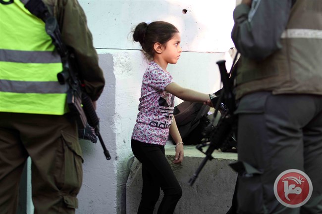 Bocah Palestina berdiri di dekat para serdadu ‘Israel’ bersenjata di pos pemeriksaan 300. Foto: Wajdi al-Jaafari/MaanImages