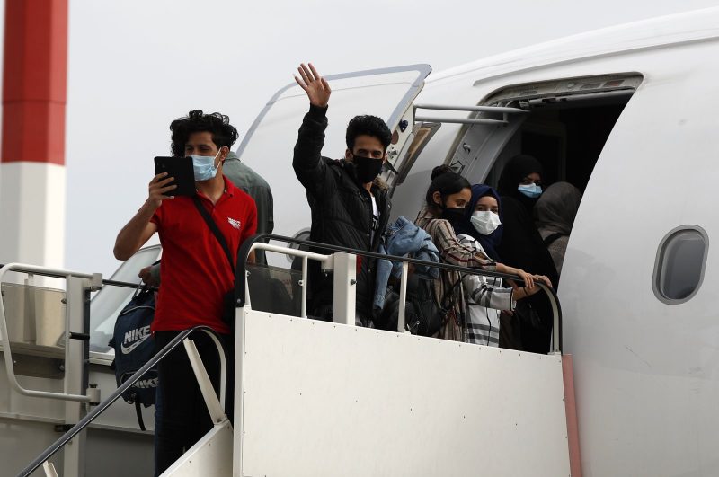 Muhajirin yang mengenakan masker untuk mencegah penyebaran coronavirus, memasuki pesawat dengan rute penerbangan menuju Inggris di Bandara Internasional Eleftherios Venizelos di Athena, 11 Mei 2020. (AP)