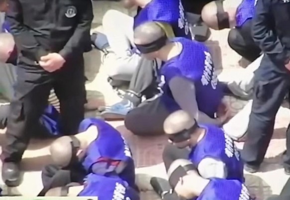 Rekaman video menunjukkan serdadu China menggiring tahanan yang ditutup matanya dan dibelenggu ke kamp penyiksaan. Sumber: The Sun