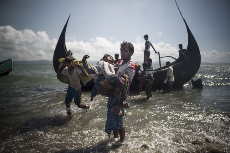 Seorang pria Bangladesh membantu muhajirin Muslim Rohingya turun dari perahu di garis pantai Bangladesh, di sungai Naf di Teknaf, setelah melintasi perbatasan dari Myanmar, 30 September 2017. (AFP)