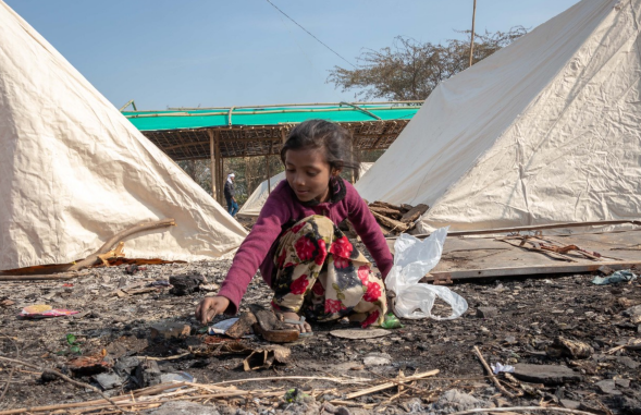 Seorang anak perempuan mencari barang-barang yang sekiranya bisa dijual untuk ditukar dengan bahan pangan. Banyak anak-anak yang bermain di lahan bekas kebakaran, di mana hal tersebut berbahaya bagi mereka. Foto: thecitizen.in 