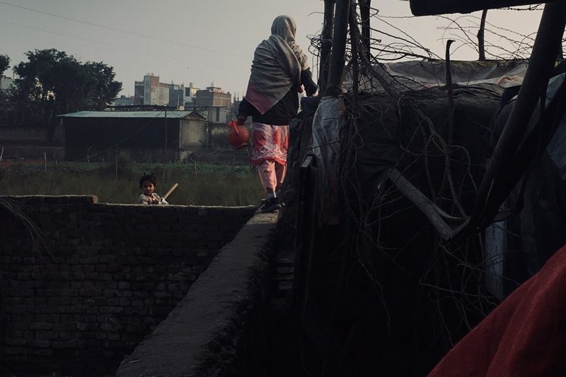 Seorang Muslimah paruh baya terlihat berjalan di atas pagar tembok. Sumber: Two Circles