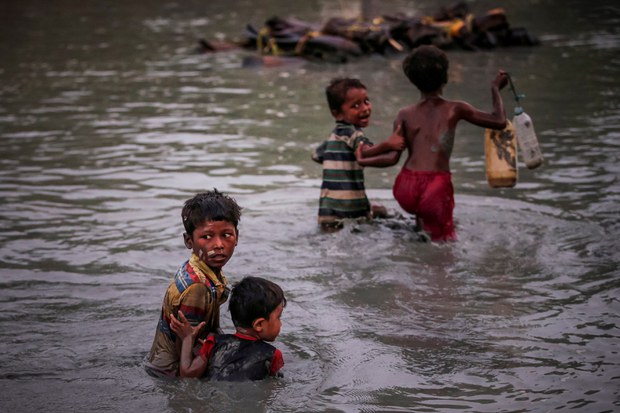 Anak-anak Rohingya yang menyelamatkan diri dari kekerasan bergandengan tangan saat mereka menyeberangi Sungai Naf di sepanjang perbatasan Bangladesh-Myanmar dekat Cox's Bazar, Bangladesh, 1 November 2017. (Reuters) 