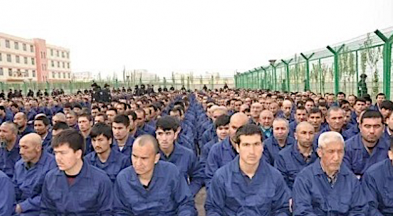 Arsip foto warga Uyghur yang disekap di sebuah kamp di Lop County, Xinjiang, sedang mendengarkan pidato. Sumber: Wikipedia Commons