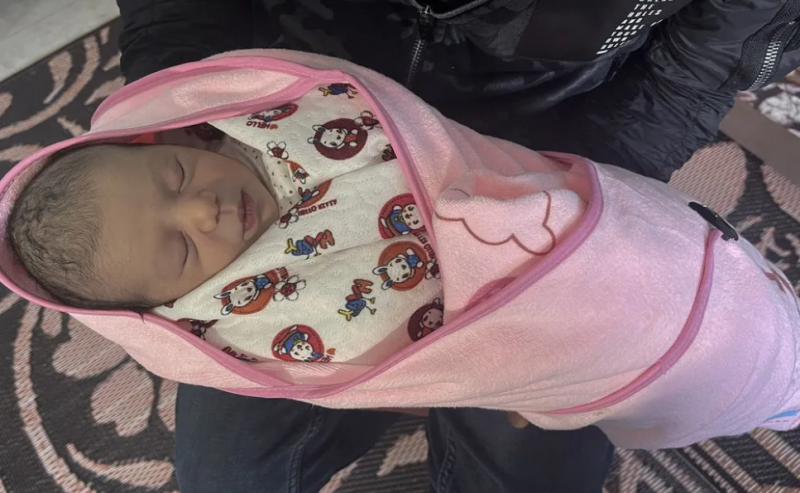 Seorang bayi perempuan Palestina yang baru lahir digendong oleh ayahnya, Muhammad Omar Mousellem. [Ali Jadallah - Anadolu Agency]