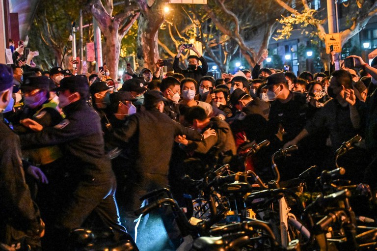 Polisi menangkap seorang pria saat aksi protes di Shanghai tanggal 27 November 2022, di mana protes terhadap kebijakan nol-Covid Cina terjadi sejak malam sebelumnya menyusul kebakaran mematikan di Urumqi, ibu kota Xinjiang. (Foto oleh HECTOR RETAMAL / AFP) 