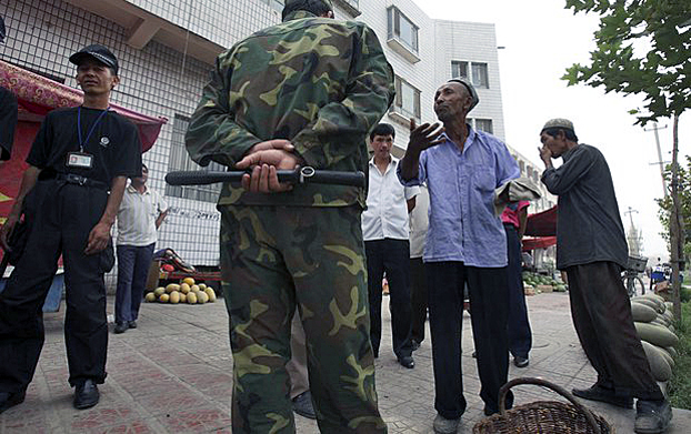Seorang petugas keamanan dari komite manajemen komunitas dan polisi menginterogasi warga Uyghur di Kashgar, provinsi Xinjiang, Cina barat laut, 6 Agustus 2018. Foto: Associated Press